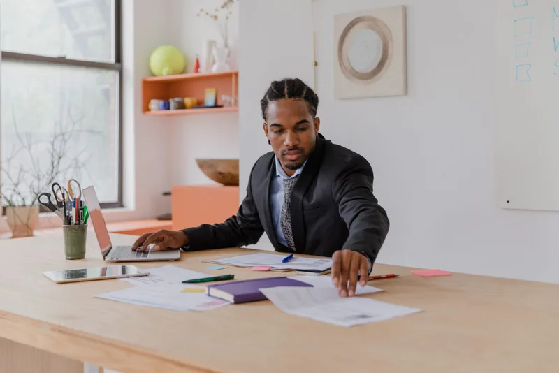 Professionnel organisant ses documents devant un ordinateur portable