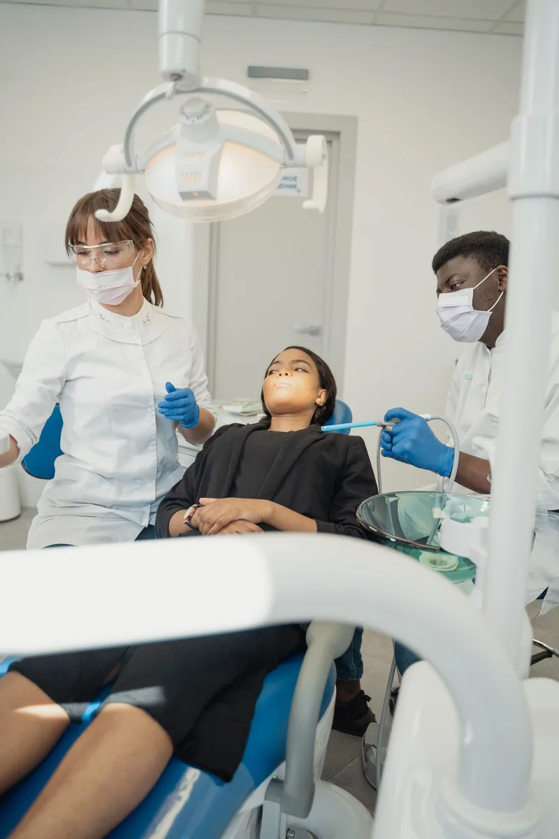 Patiente accompagnée par deux professionnels dans un cabinet dentaire