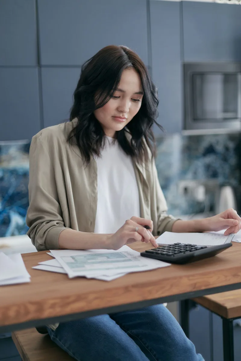 Femme faisant ses comptes avec des documents et une calculatrice