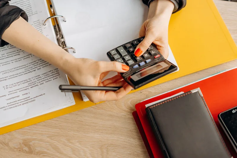 Mains utilisant une calculatrice sur une table de travail